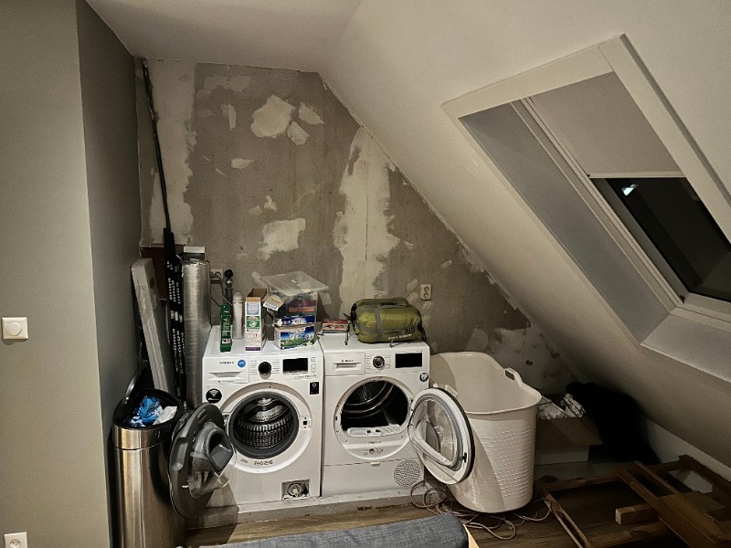 Wasruimte onder een schuin dak met een wasmachine en droger en een dakraam.