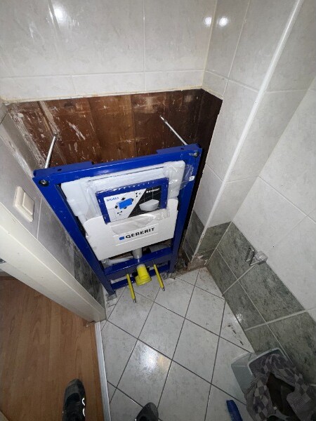 Toilet in aanbouw met een blauw inbouwreservoir zichtbaar in de muur.
