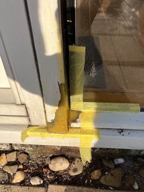 Dezelfde kozijnhoek opgevuld met amberkleurig houtreparatiemiddel, nog afgeplakt.