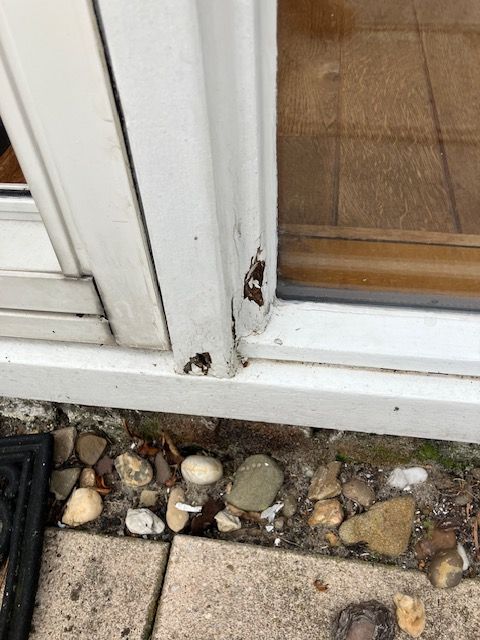 Close-up van een kozijnhoek bij een buitendeur met zichtbaar houtrot.