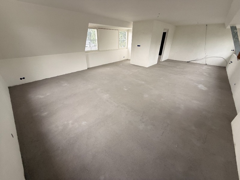 Afgewerkte vliering met witgeschilderde wanden en plafond en een dakkapel met twee ramen.